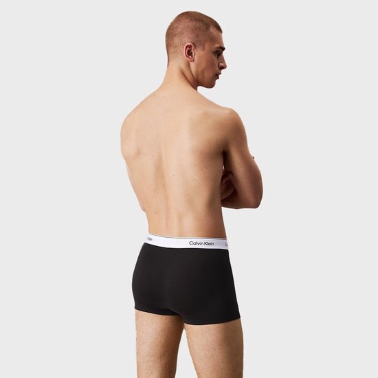Man van achteren gezien, draagt een zwarte Calvin Klein boxer met witte tailleband met logo.