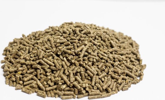 Een hoopje bruine, cilindervormige kippenvoer pellets op een witte achtergrond.
