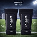 Zwarte Vynix Ballers scheenbeschermers van 14x7cm, op een voetbalveld.