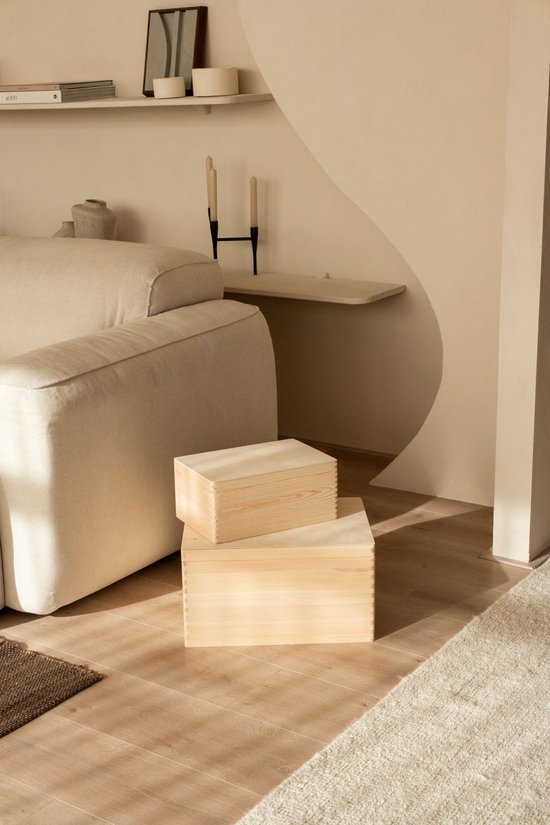 Twee naturel houten kisten op een houten vloer naast een beige bank.
