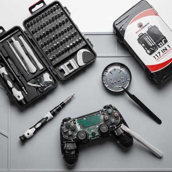 Een open precisieschroevendraaierset met 117 stuks ligt naast een gedemonteerde gamecontroller.