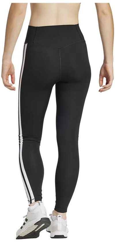 Achterkant van een model in zwarte legging met witte Adidas strepen en witte sneakers
