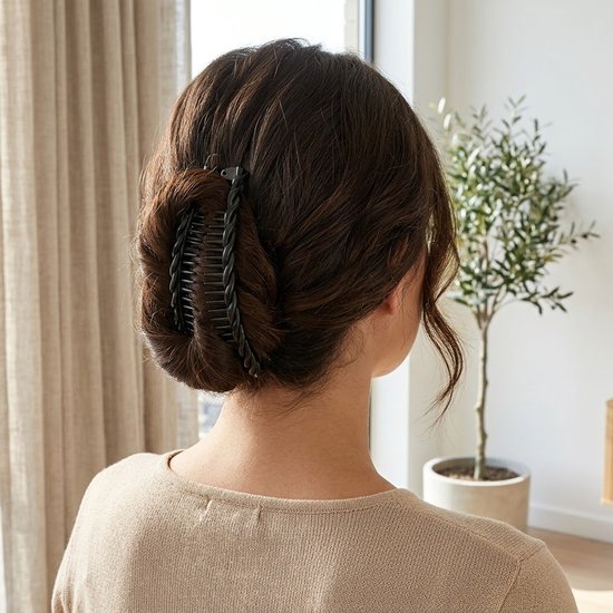 Een vrouw met donkerbruin haar draagt een zwarte haarclip in een opgestoken kapsel.