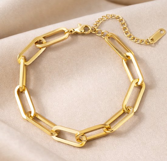 Bracelet à maillons dorés rectangulaires sur un tissu crème.