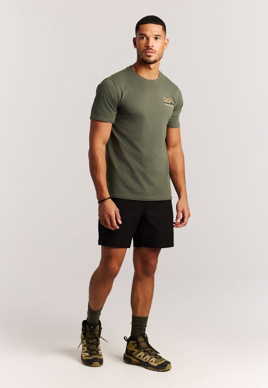 Man, van voren gezien, in een groen T-shirt met een opdruk van een berglandschap op de borst en een zwarte broek.