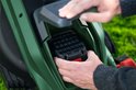 Groene Bosch grasmaaier, een hand plaatst de accu.