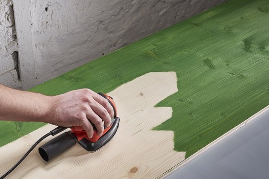 Hand schuurt groen geverfd hout, waarbij een deel van de groene verf wordt verwijderd.