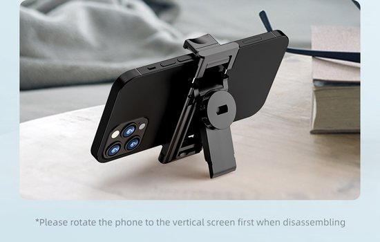 Zwarte smartphone op een zwarte selfie-stick houder op een tafel.