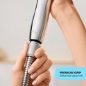 Vrouw handen houden het chroomkleurige handvat van de douchekop vast. Tekst: Premium Grip, Gekarteld oppervlak.
