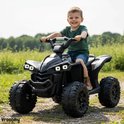 Zwarte kinderquad met een jongetje erop. De quad heeft robuuste wielen en schokdempers.