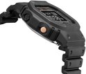 Detail van de zijkant van een zwart G-Shock horloge met een koperkleurige knop en een zwart bandje.