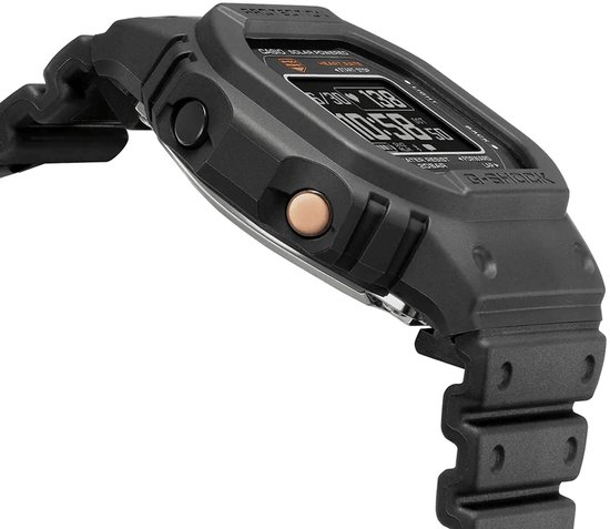 Detail van de zijkant van een zwart G-Shock horloge met een koperkleurige knop en een zwart bandje.