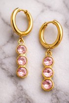 Gouden oorringen met een hangertje van drie roze steentjes.