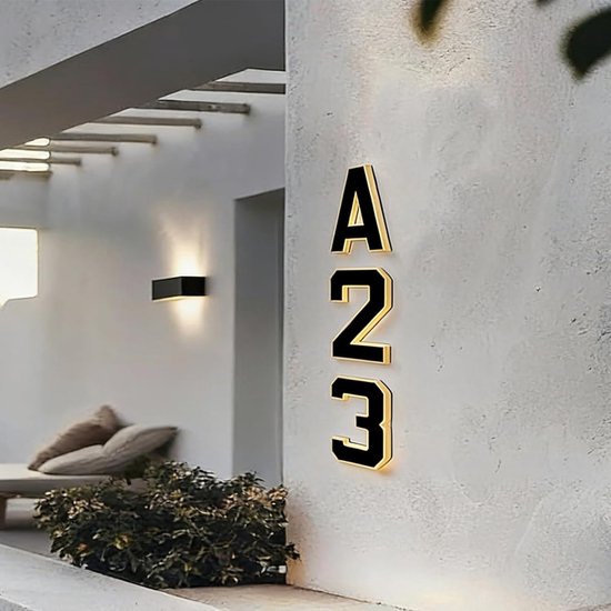 Zwarte, gouden randen 'A23' huisnummers op een witte muur, verlicht.