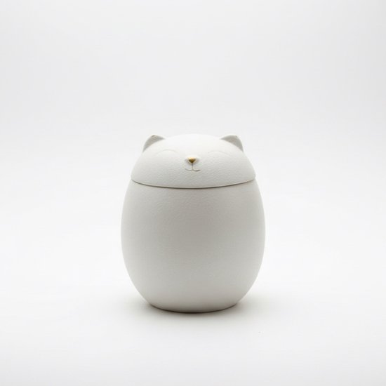 Witte keramische urn in de vorm van een kat, met gesloten oogjes en gouden neus.