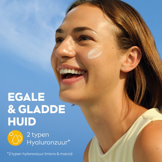 Vrolijke jonge vrouw lacht naar de camera met een witte crème op haar wang. Tekst: "EGALE & GLADDE HUID", "2 typen Hyaluronzuur".