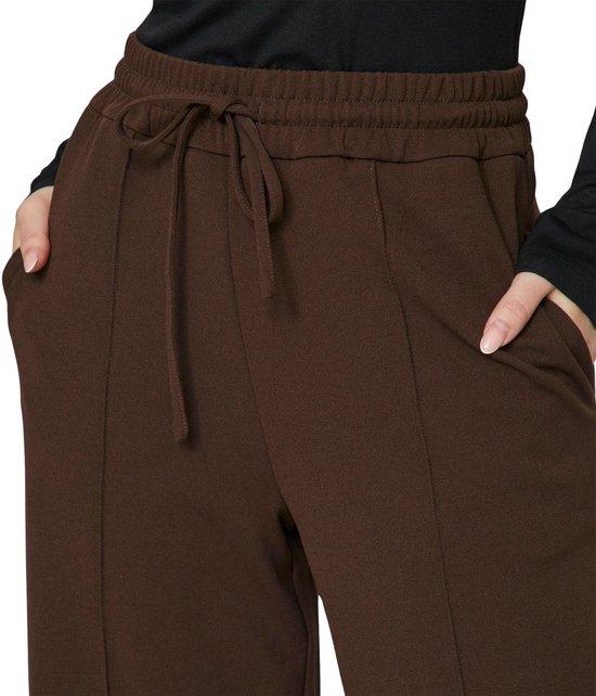 Detailopname van een donkerbruine wijde broek met trekkoord in de taille en steekzakken.