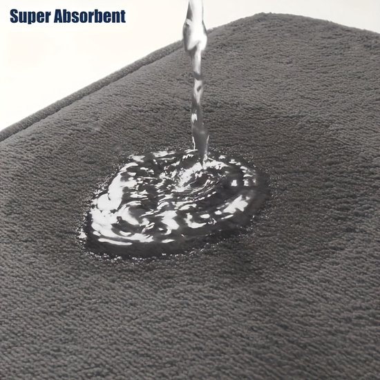 Donkergrijze badmat met "Super Absorbent" tekst, water wordt snel opgenomen.
