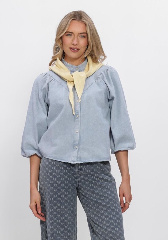 Model met lichtblauwe denim blouse met ballonmouwen en gele sjaal, gedetailleerde foto.