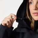 Gros plan sur la capuche d'un manteau noir, une main ajustant le cordon de serrage.