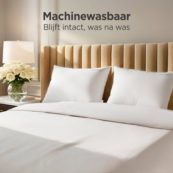 Twee witte CozySense kussens op een opgemaakt bed met beige hoofdbord. 'Machinewasbaar'.