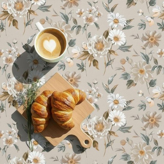 Beige tafelkleed met bloemenprint, met twee croissants en een kopje koffie.