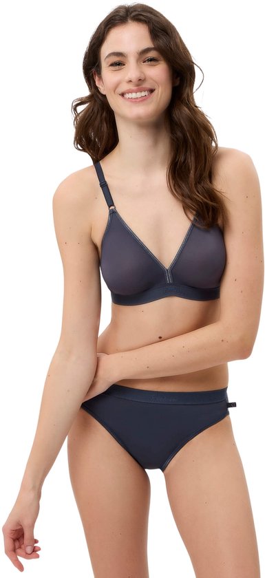 Model in een grijze beugelvrije bh met naden en een elastische band, en bijpassende slip.