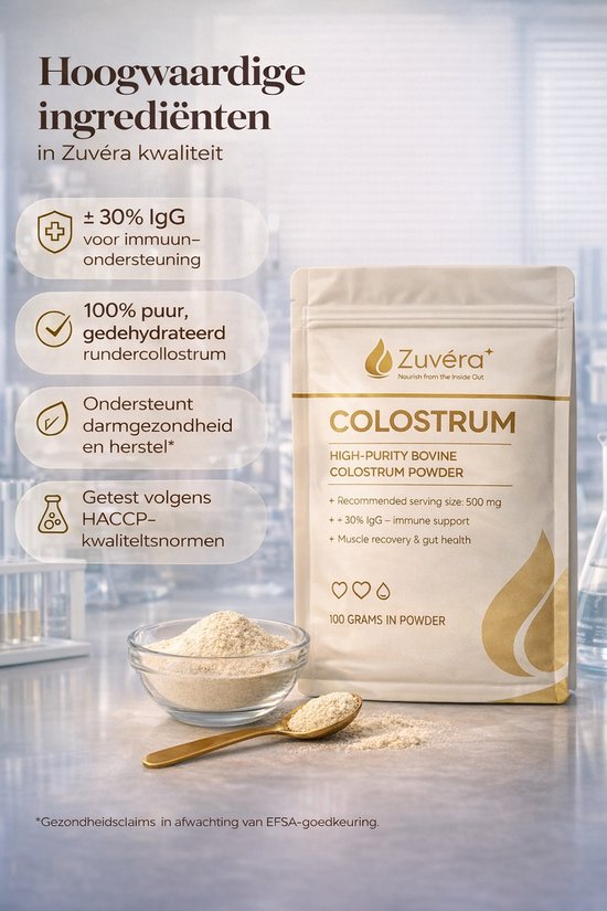 Een beige zak met "Zuvéra Colostrum" staat naast een glazen kom gevuld met poeder en een gouden lepel. Tekst over ingrediënten en kwaliteit.