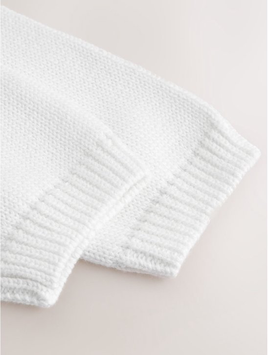 Mouwen van witte babyvest met geribbelde boorden.
