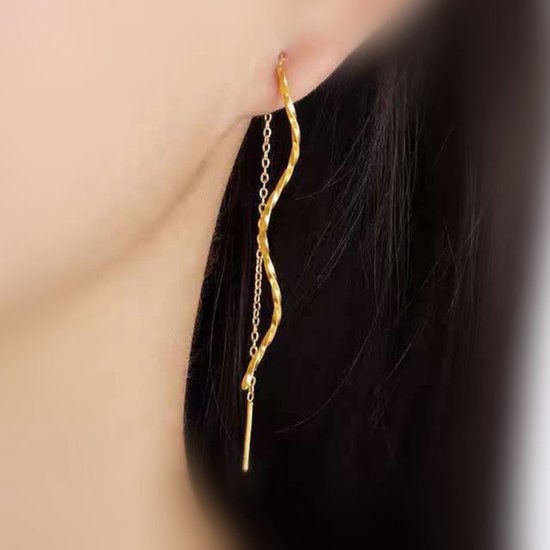 Gouden doortrekoorbellen met gedraaide staaf en fijne ketting, gedragen in een oor.