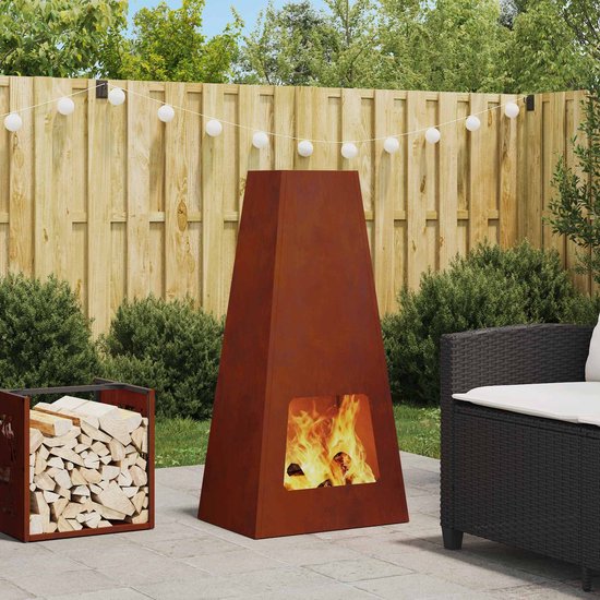 Roestige conische vuurkorf met brandend vuur, naast een houtopslag, op een terras.