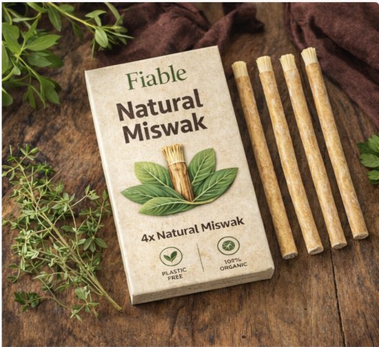 Fiable Natural Miswak: 4x natuurlijke miswak stokjes naast een verpakking met bladeren, op een houten ondergrond met takjes.