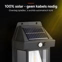 Zwarte solar buitenlamp met zonnepaneel, bewegingssensor en zichtbare LED-lamp.