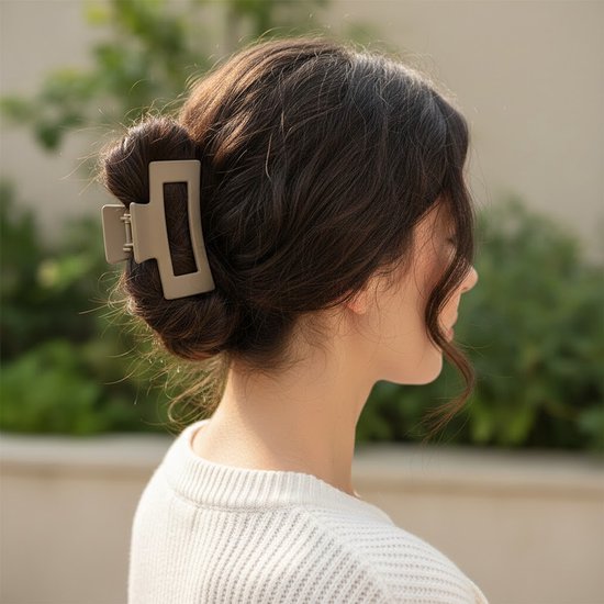 Lichtgrijze haarclip in een knot bij een vrouw met donkerbruin haar.
