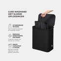 Zwarte gewatteerde wasmand met deksel en uitneembare binnenzak. De binnenzak wordt uit de mand getild.
