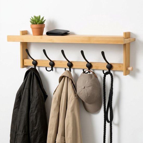 Houten kapstok met plank en 5 zwarte haken, met jas, pet, portemonnee en plant.