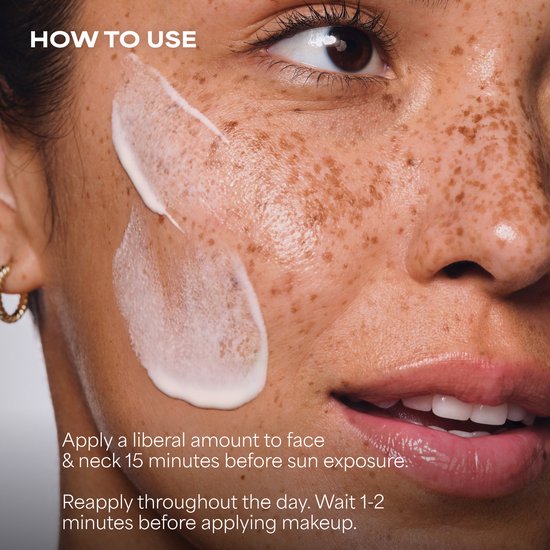 Extreme close-up van een gezicht met sproeten met witte crème aangebracht op de wangen, met de tekst 'HOW TO USE'.