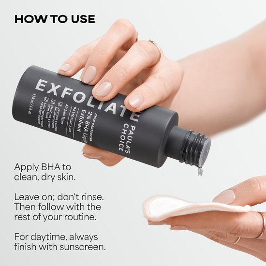 Handen houden een flesje Paula's Choice 2% BHA Liquid Exfoliant en een wattenschijfje vast.