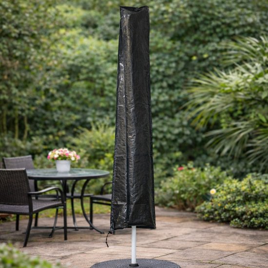 Zwarte, rechthoekige parasolhoes op een voet in een tuin met stoelen en tafel.
