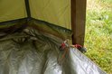 Interieur van een groene tent met een ritsbare bodem en grondzeil, gras op de achtergrond.