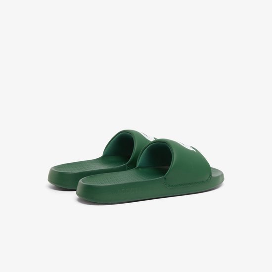 Donkergroene Lacoste slides met witte krokodillenlogo's. De zool is voorzien van een rasterpatroon.