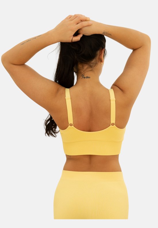 Achterkant van een model met een gele bustier met ribbelstof en verstelbare bandjes.