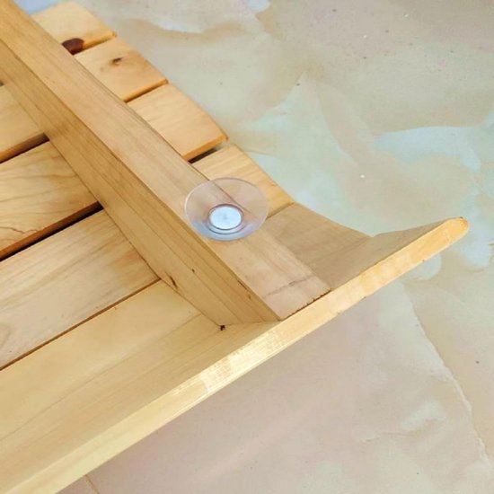 Detail van de houten opklapbare kruk, met een transparante zuignapbevestiging aan de zijkant.