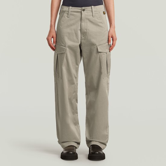 Model van voren in een lichtgrijze cargo broek met grote opgestikte zakken op de zijkant.