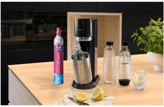 Keuken aanrecht met Sodastream machine, flessen, glas en citroen.