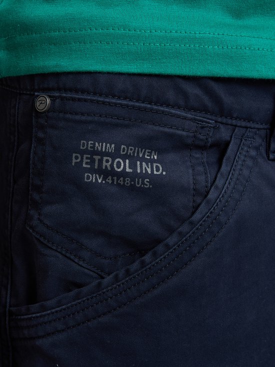Donkerblauwe cargobroek met zakdetail en tekst: 'DENIM DRIVEN PETROL IND. DIV.4148-U.S.'.