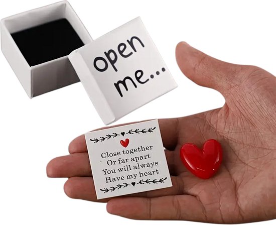 Hand met een rood hars hartje en een kaartje met 'Close together Or far apart You will always Have my heart'. Open wit doosje ernaast.
