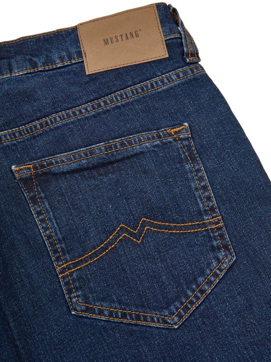 Achterkant donkerblauwe jeans met oranje stiksels op de zakken en een bruin Mustang-label.