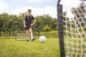 Jongen in sportkleding trapt tegen voetbaldoel met bal