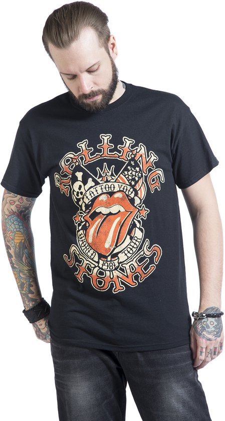 Man met tatoeages op de armen draagt een zwart T-shirt met rode en beige "Tattoo You World Tour 1981" opdruk.